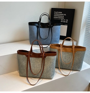 Three multi-color denim tote bags with leather handles displayed on a white step podium