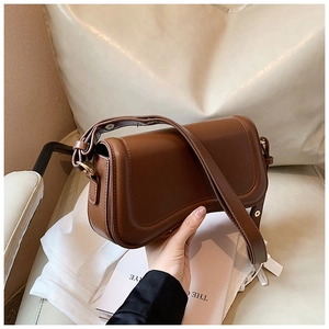 Close-up of a brown leather shoulder bag with a stylish flap and embossed stitching detail