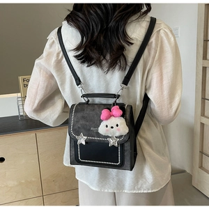 Detail of vintage gray backpack with pearl rivet edges and a plush rabbit pendant