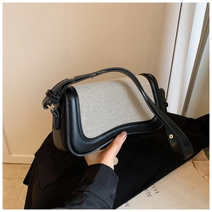 Detail of a black and white baguette shoulder bag with adjustable strap and gold buckle