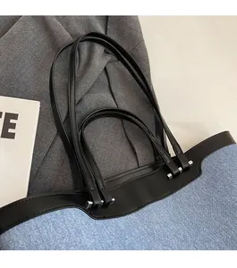 Detail of blue denim tote bag shoulder strap connection with silver metal buckles
