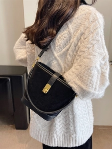 Retro black matte bucket bag with gold hardware worn over a cream knit sweater