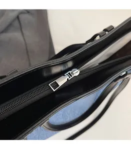 Detailed close-up of smooth silver metal zipper on premium black leather tote bag
