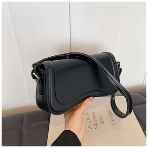 Detail of a black leather crossbody bag with a magnetic flap and golden metal buckle