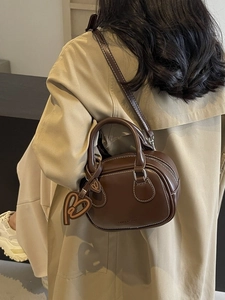 Dark brown leather bowling bag with contrast stitching and shoulder strap for women