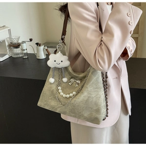 Detail of green faux leather tote bag with silver chain, pearls and plush cloud charm