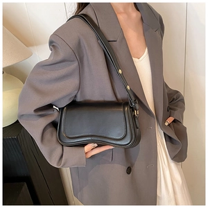 Detail of adjustable leather strap and golden metal hardware on a black underarm bag