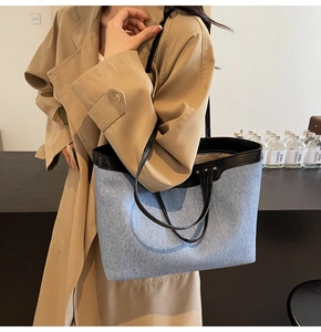 Detailed view of denim tote bag with leather trim and handle on female model