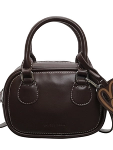 Classic dark brown bowling handbag with contrast stitching and heart charm on white background