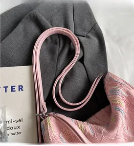 Detail of pink textured handbag with rainbow embroidery on a grey blazer and magazine