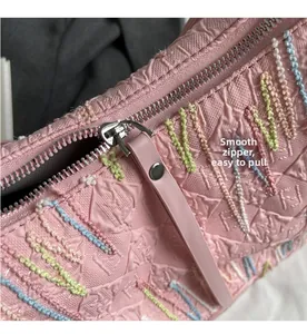Detail of the pink tote bag featuring smooth metal zipper and 3D wavy embroidery pattern