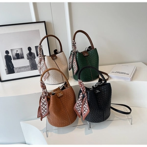 Detail view of four trendy mini bucket bags in cream, green, brown and black with silk scarves