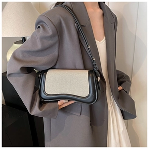 Detail of minimalist contrast shoulder bag featuring white canvas and black wavy leather base