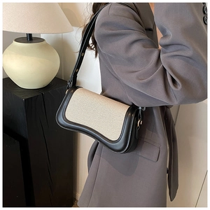 Detail view of the black leather and beige canvas patchwork bag with curved base