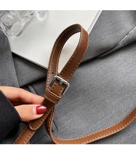 Detail of adjustable brown leather strap with silver buckle and fine stitching