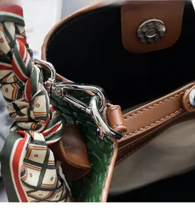 Detail of brown leather bucket bag with green weave, silver magnetic clasp and silk scarf