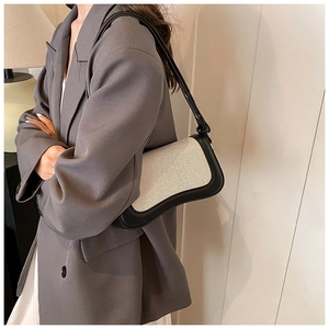 Detailed view of canvas and black leather contrast on crossbody bag with wavy bottom