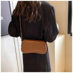 Detail of adjustable gold buckle and smooth caramel leather on minimalist crossbody bag