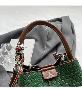 Detail of green woven texture handbag featuring decorative scarf and durable brown handle