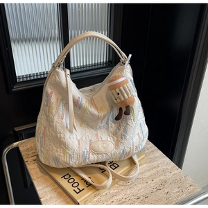 Detail of white wrinkled hobo bag with wave embroidery and cute coffee cup plush charm