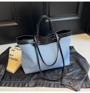 Detail of blue denim tote bag with black leather straps on a stylish dark background