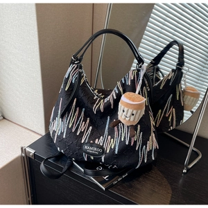 Detail of black hobo bag with colorful wave embroidery and cute plush coffee cup charm