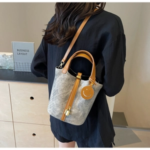 Detailed back view of a grey bucket bag with brown leather straps and gold lock detail
