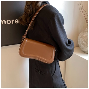 Detailed view of a brown leather underarm bag worn with a black blazer for a chic look