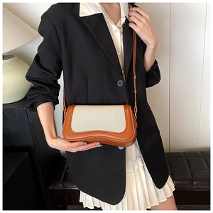 Detail of minimalist beige canvas and brown leather crossbody bag styled with a blazer