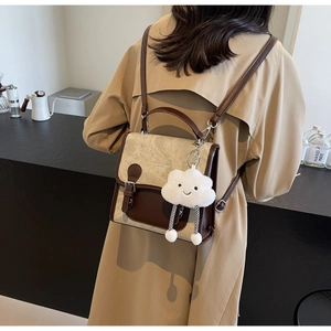Detalle de mochila vintage beige y marrón con amuleto de nube y hebillas decorativas