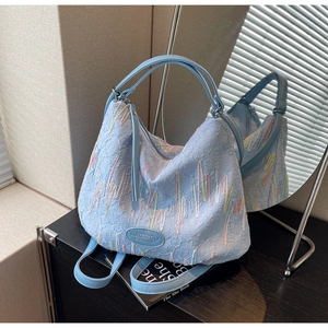 Detail of light blue shoulder bag with multi-color embroidery and FF texture
