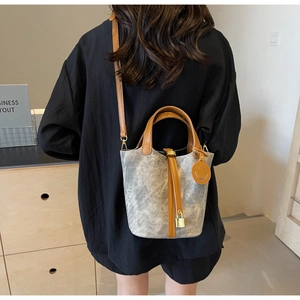 Detail of grey bucket bag with brown handles, golden lock pendant and smile tag