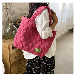 Detail of rose red corduroy tote bag featuring quilted pattern and ruffled shoulder strap