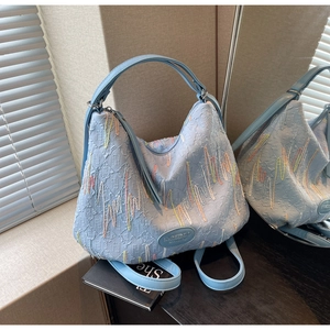 Detailed view of light blue hobo bag with jacquard texture and rainbow wave embroidery