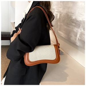 Detail of brown leather and beige canvas underarm bag with unique wavy curve bottom edge