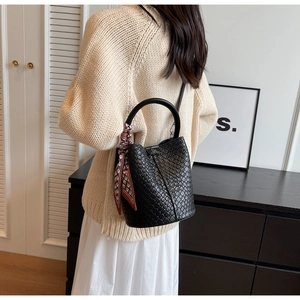 Detail of black woven bucket bag with silk scarf and circular top handle design