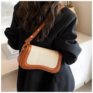 Detail of canvas and brown leather underarm bag with unique wave bottom design on model