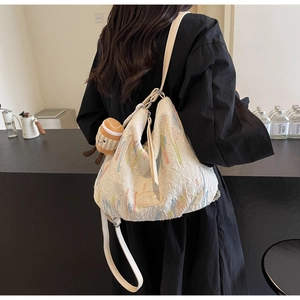 Close-up of white canvas tote with colorful embroidery and plush burger charm detail