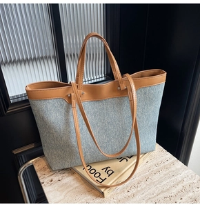 Detailed shot of large denim tote bag with brown leather handles and dual strap design