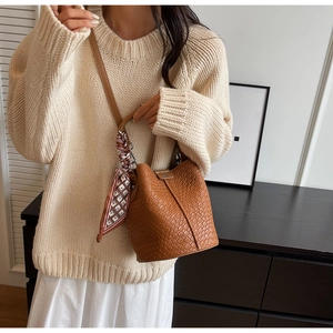 Brown bucket bag with woven texture and geometric silk scarf accessory on a model