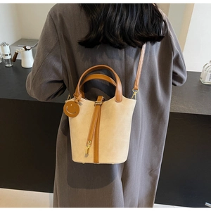Detail of canvas bucket bag with leather trim and brown smiley face charm pendant