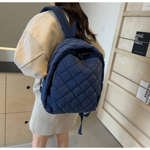 Detail des dunkelblauen gesteppten Rucksacks mit leichtem Stoff und Rückenansicht am Modell