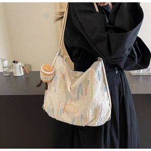 Detail of off-white tote bag with colorful embroidery and plush doll charm