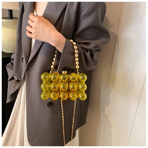 Detailed macro view of yellow acrylic box bag with 3D bubble texture and gold bead handle