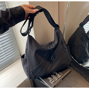 Close-up of black canvas hobo bag with multiple zip pockets and adjustable strap detail