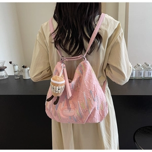 Pink quilted backpack showing colorful embroidery details and fashionable plush charm