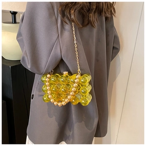 Detail of yellow acrylic bubble bag with golden metal chain on a grey blazer outfit