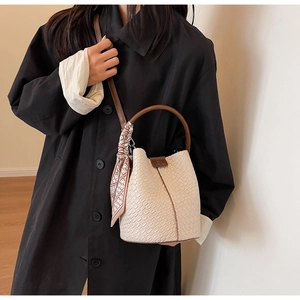 Detail of cream crocodile pattern bucket bag with brown handle and silk scarf decor