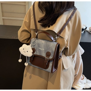 Detalle de mochila de tela vaquera y cuero con colgante de nube y textura de correa