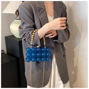Detail of blue acrylic bubble bag with golden bead handle and metallic chain strap